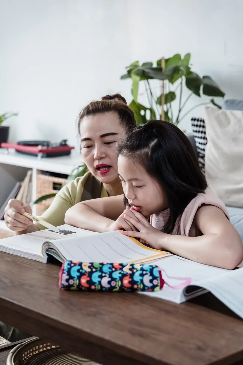 A patient teacher guiding a young girl through a reading exercise