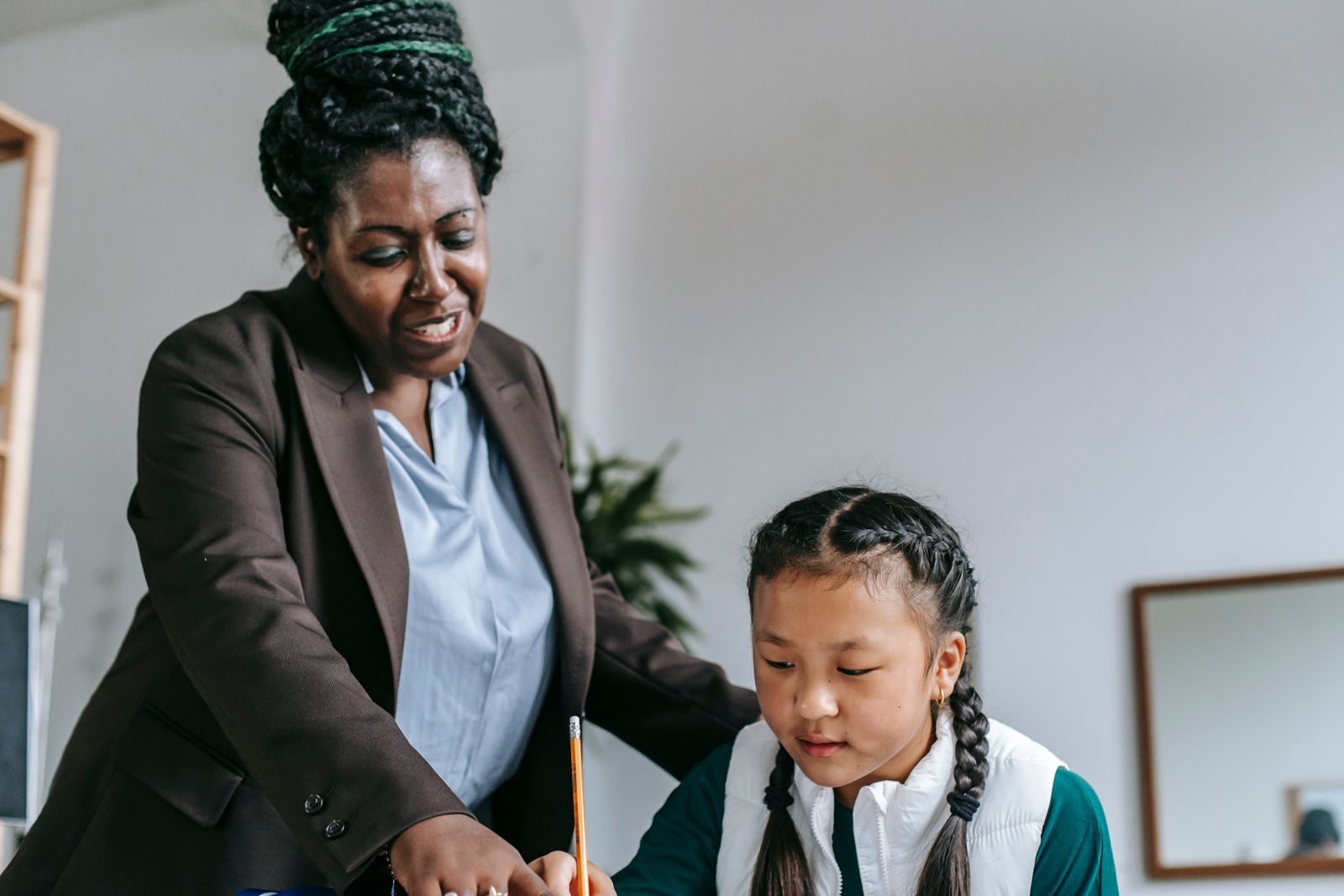 A teacher working one to one with a smiling student at a classroom desk