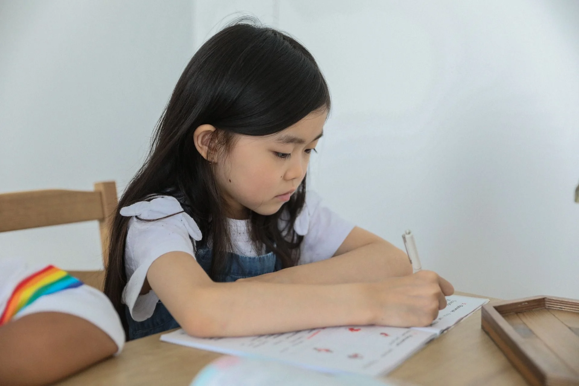 Student concentrating on Additional Mathematics homework at a desk