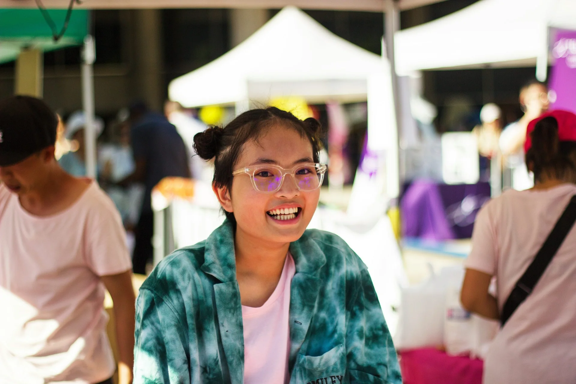 Teenage student in glasses smiling at an outdoor event