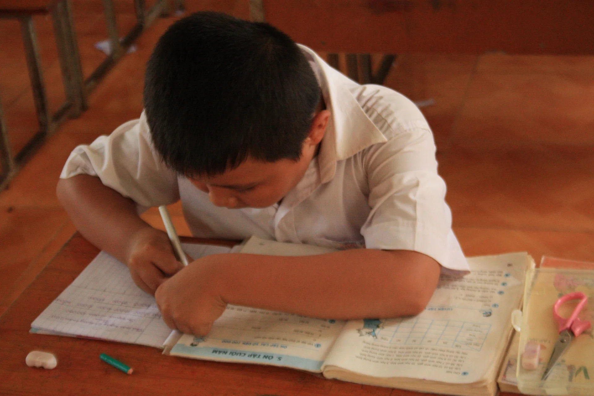 A student focused on a written task in a classroom